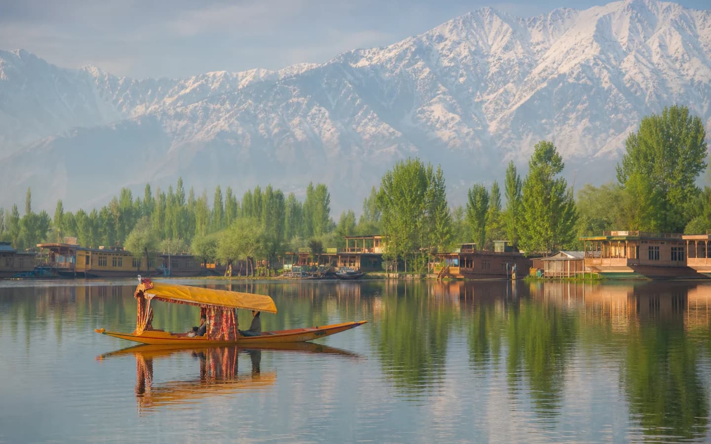 Traditional shikara crossing Dal Lake with Kashmir mountains beyond