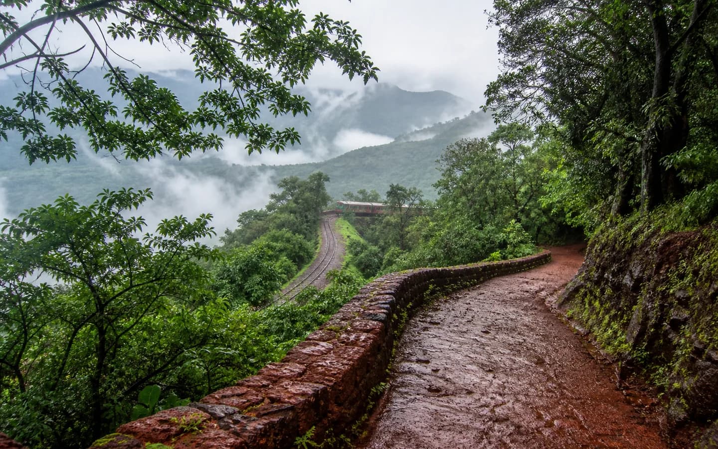 Rain-washed red trail through the green hills of Matheran